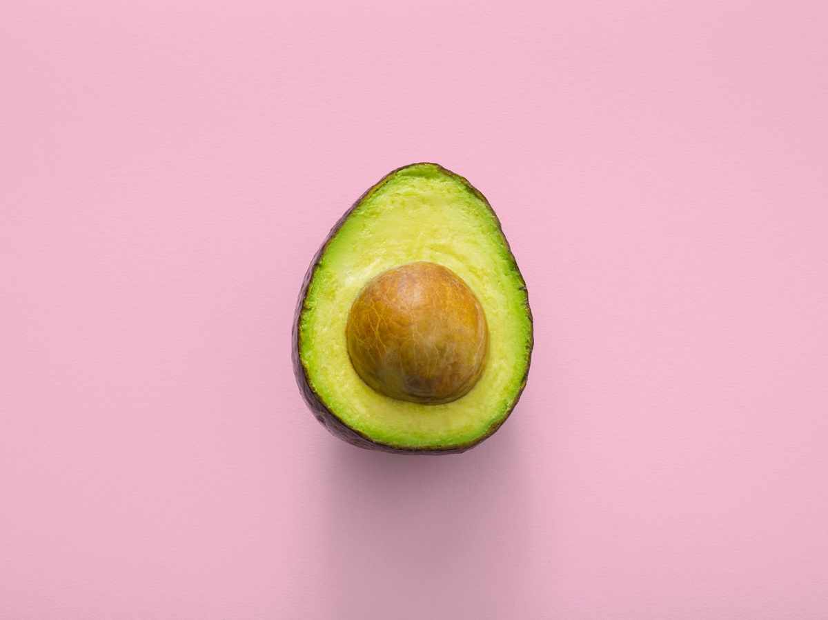 Avocado on a pink background - you can get many foods which provide protein and fat in a vegan diet