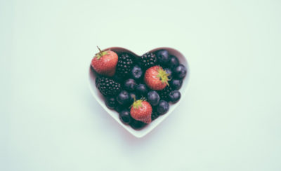 A heart-shaped bowl filled with strawberries and blueberries.