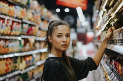 Woman reaching for a product on a supermarket shelf