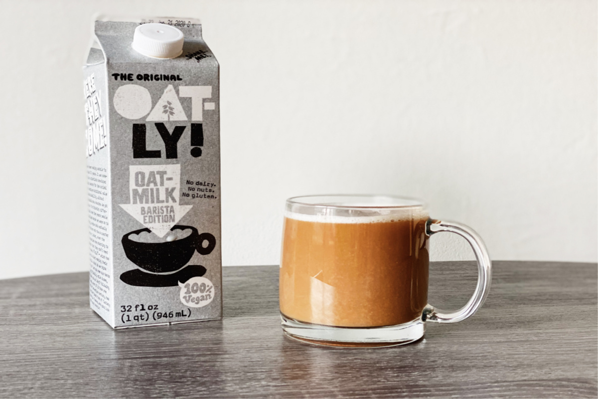 Oatly milk alongside a coffee. Plant milk is one of the key vegan food essentials to look out for in the supermarket. 
