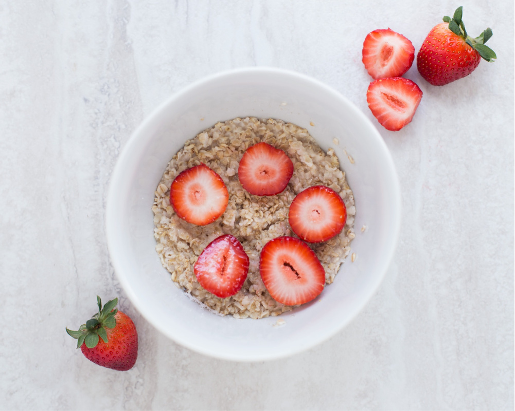 A bowl of oatmeal accompanied by strawberries