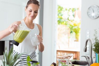 Woman pouring smoothie into glass