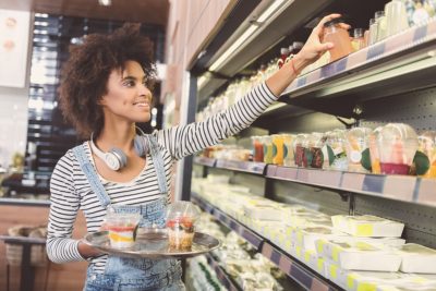 Cheerful young woman is choosing foodstuffs