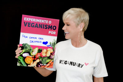 Xuxa segurando o cartaz de Veganuary que diz Experimente o veganismo por amor aos animais