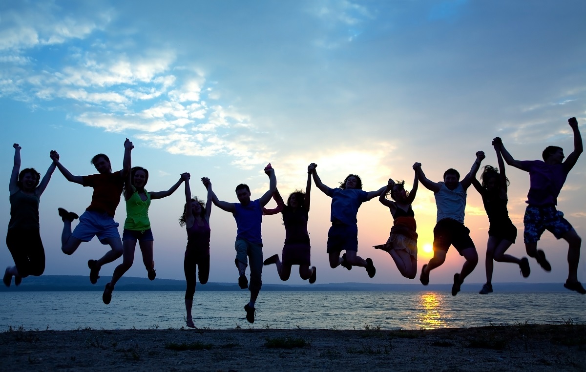 A group of friends holding hands and jumping up in the air