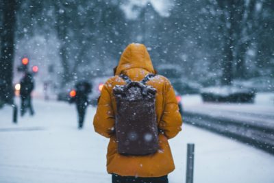 Woman in snow wearing coat and backpack