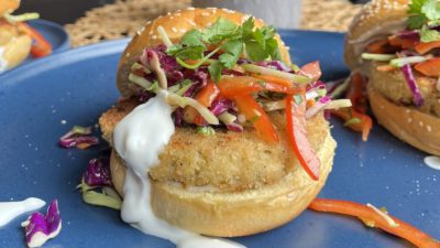 A sandwich bursting with fillings of slaw and lime mayo atop a Hungry Planet Crab Cake