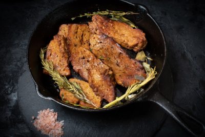 Roasted seitan in cast iron pan with various herbs and spices
