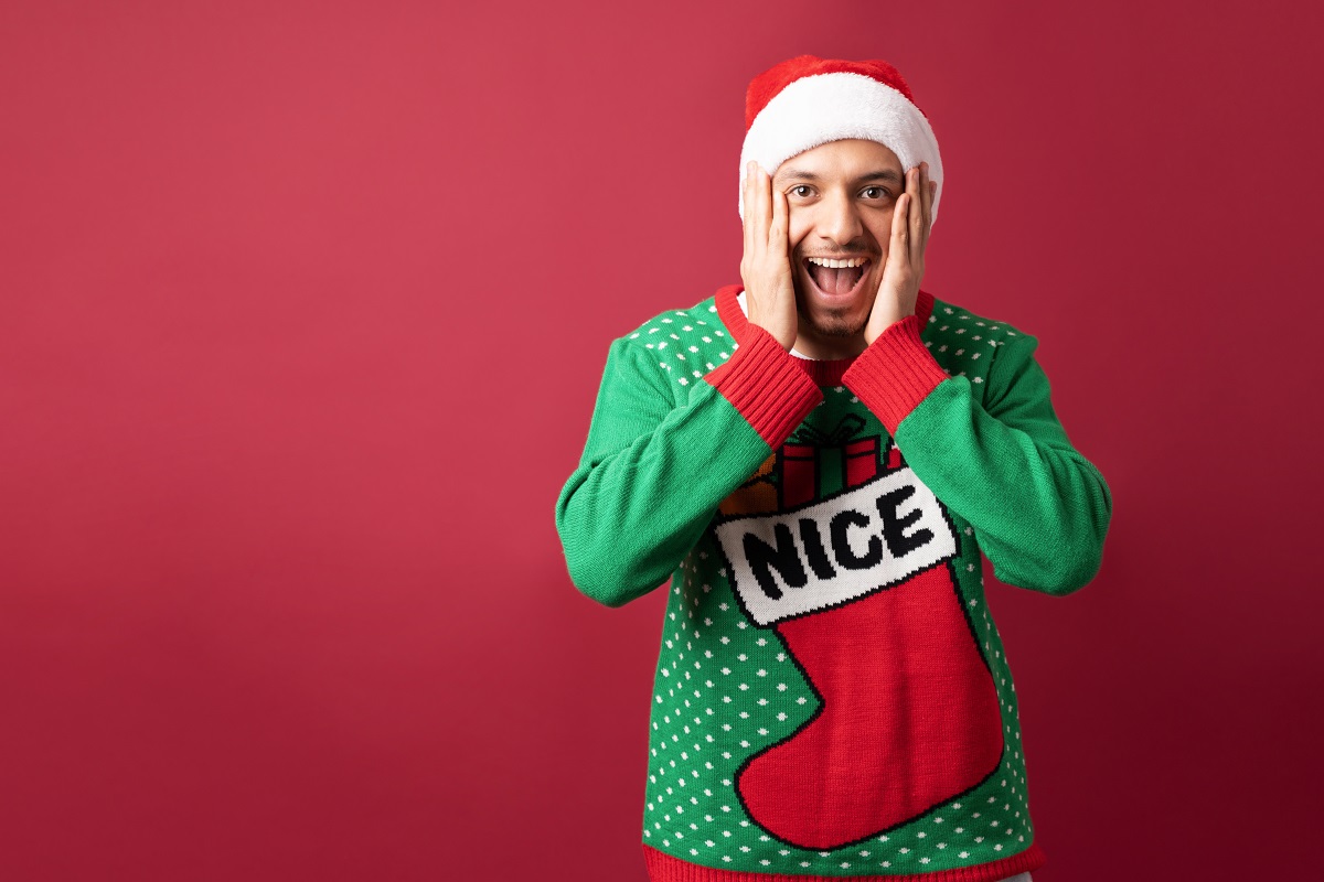 Man with ugly sweater opening his mouth and looking surprised about some awesome Christmas sale