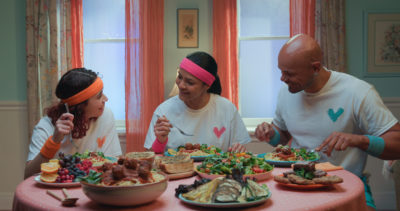 A family is seated at a table covered in an assortment of delicious vegan food