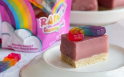 A rainbow gummy sits atop a pink cake bar with a shortbread crust