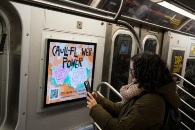 Subway rider in NYC viewing Veganuary's ads