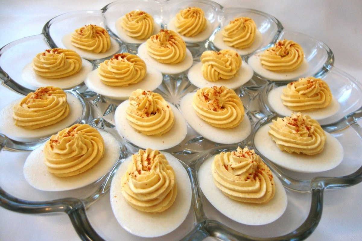 A platter of vegan egg halves with perfectly piped yellow deviled yolks