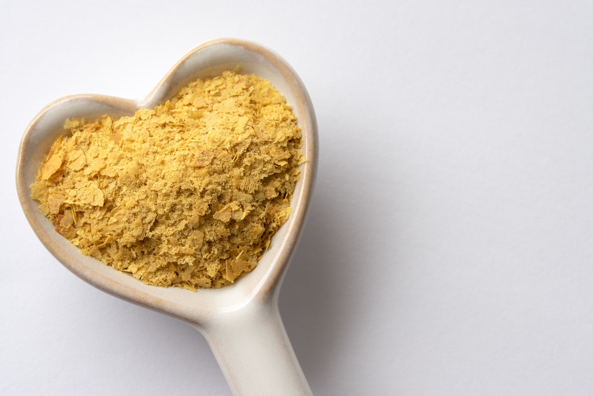 Nutritional yeast flakes in a white, heart-shaped spoon