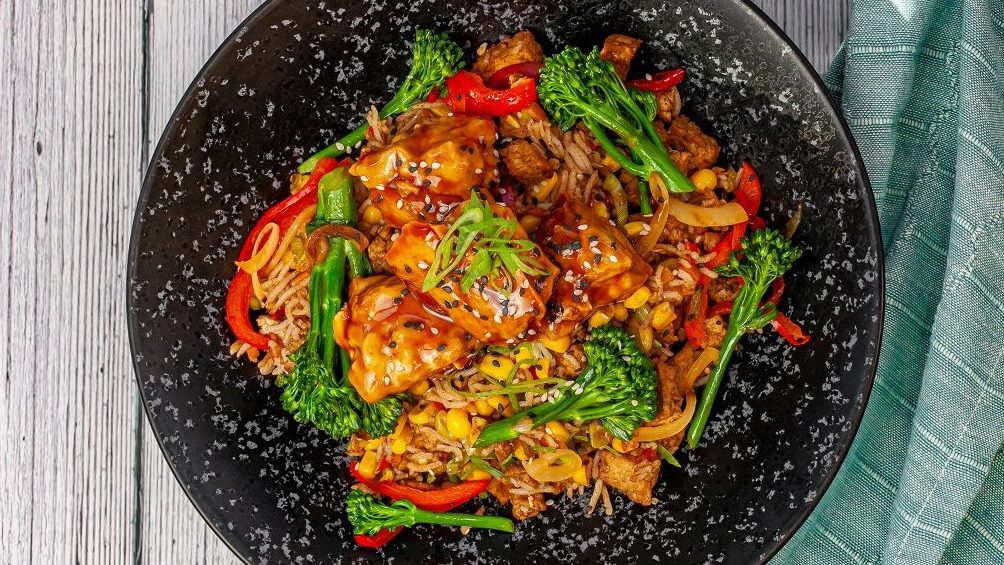 sweet and sour air fryer tofu marinade on a bed of vegetables and rice 