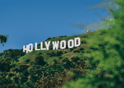 The Hollywood sign is on a green hill on a beautiful day with a perfectly blue sky