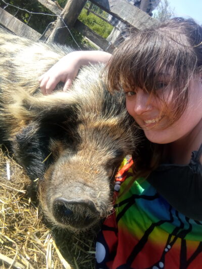 Luna - Veganuary Participant. Luna with a rescued pig at The Retreat Animal Rescue in Kent